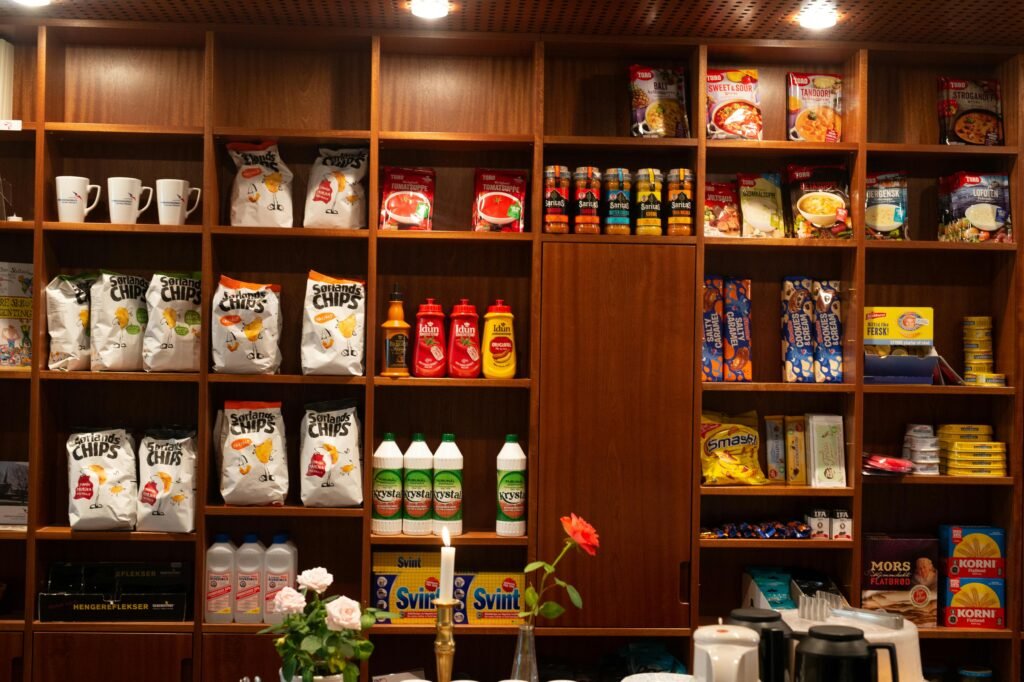 pexels-photo-3167310-3167310 Wide array of packaged groceries neatly arranged on wooden shelves in a store setting.